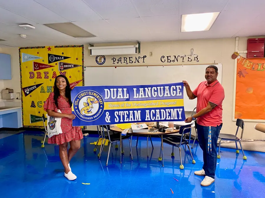 Staff holding a Dual Language and STEAM Academy banner printed in-house